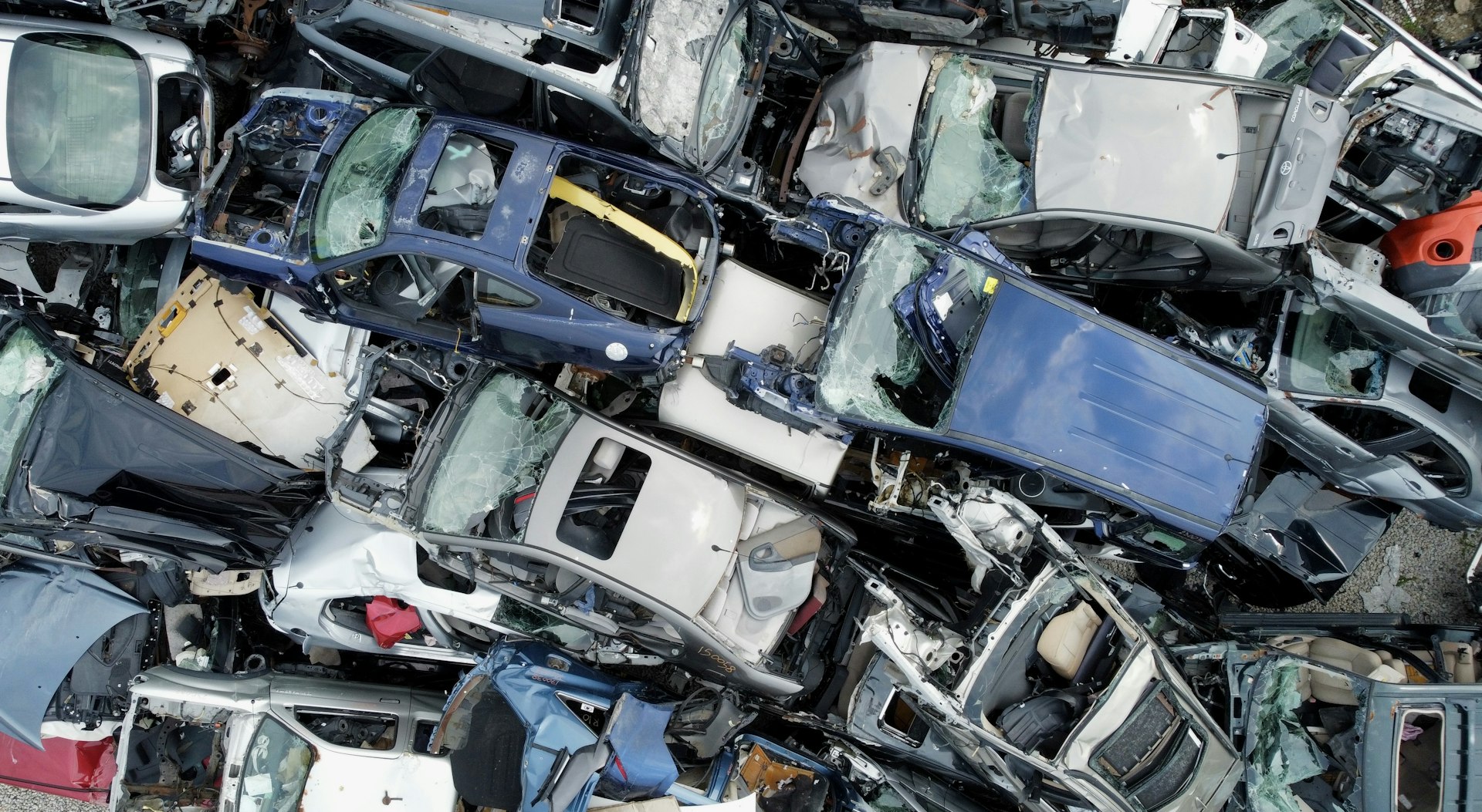Luftaufnahme eines Verwertungsplatzes mit dicht gestapelten Fahrzeugwracks