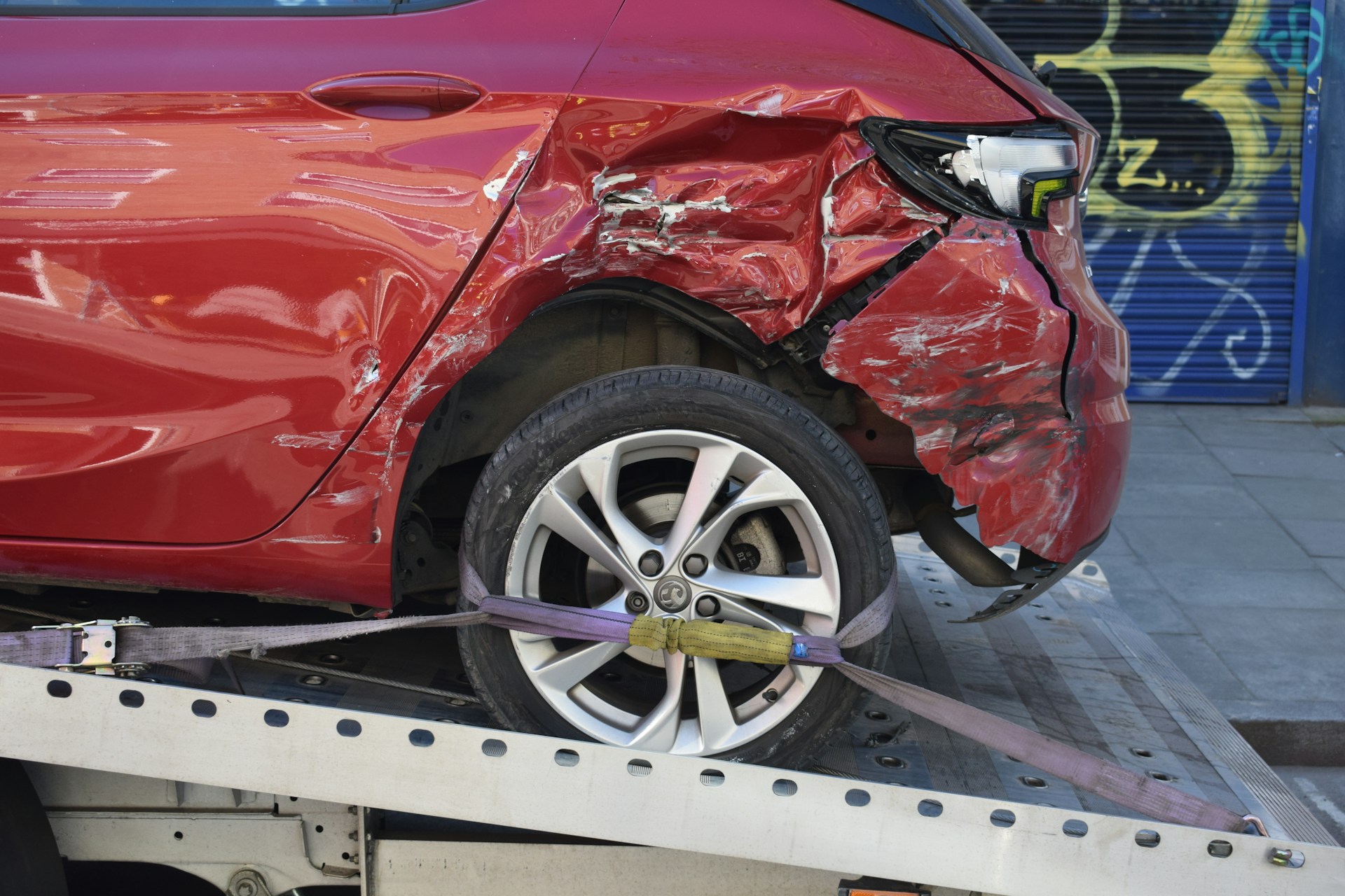 Unfallbeschädigtes Auto wird auf der Ladefläche eines Abschleppwagens verzurrt